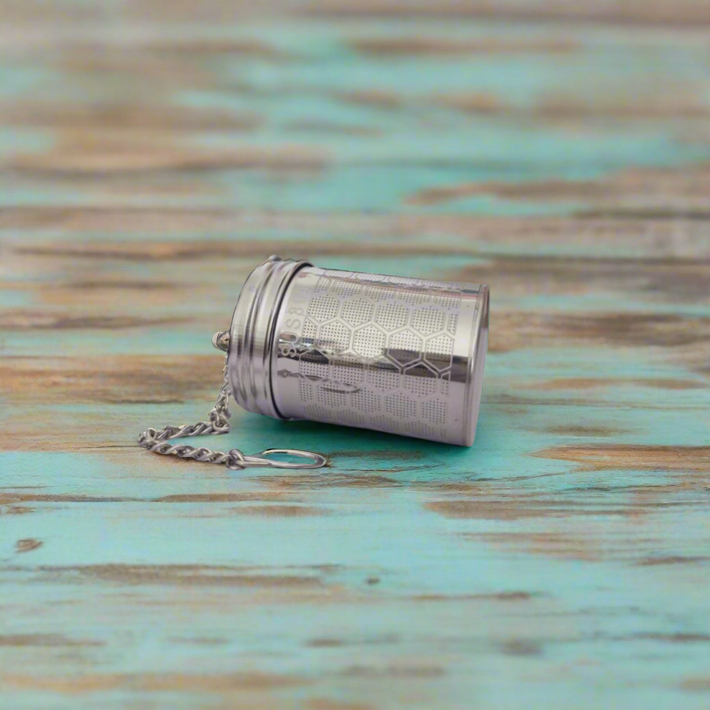 Silver tea ball infuser on a light gray background
