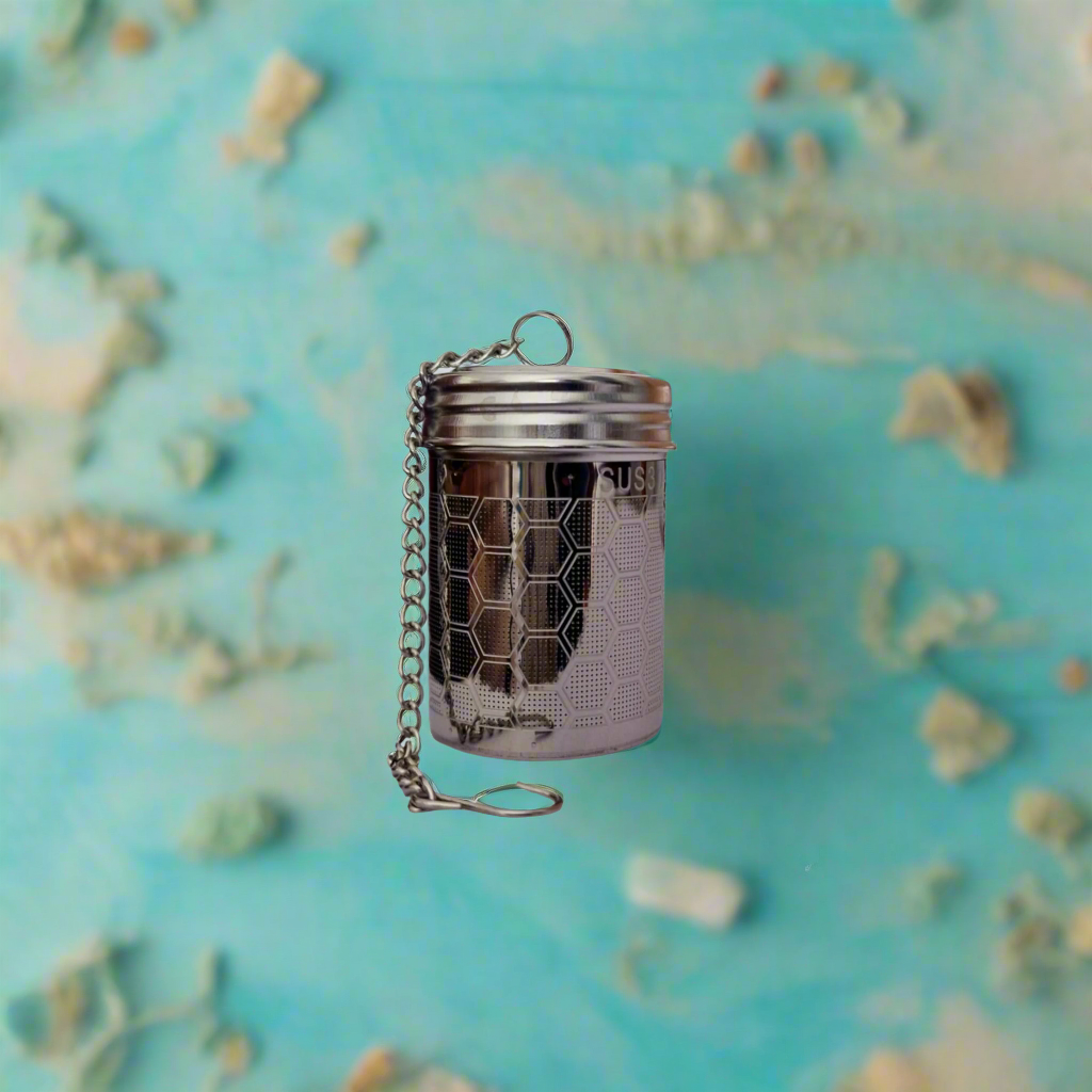 Metallic tea infuser with honeycomb design on a textured blue background